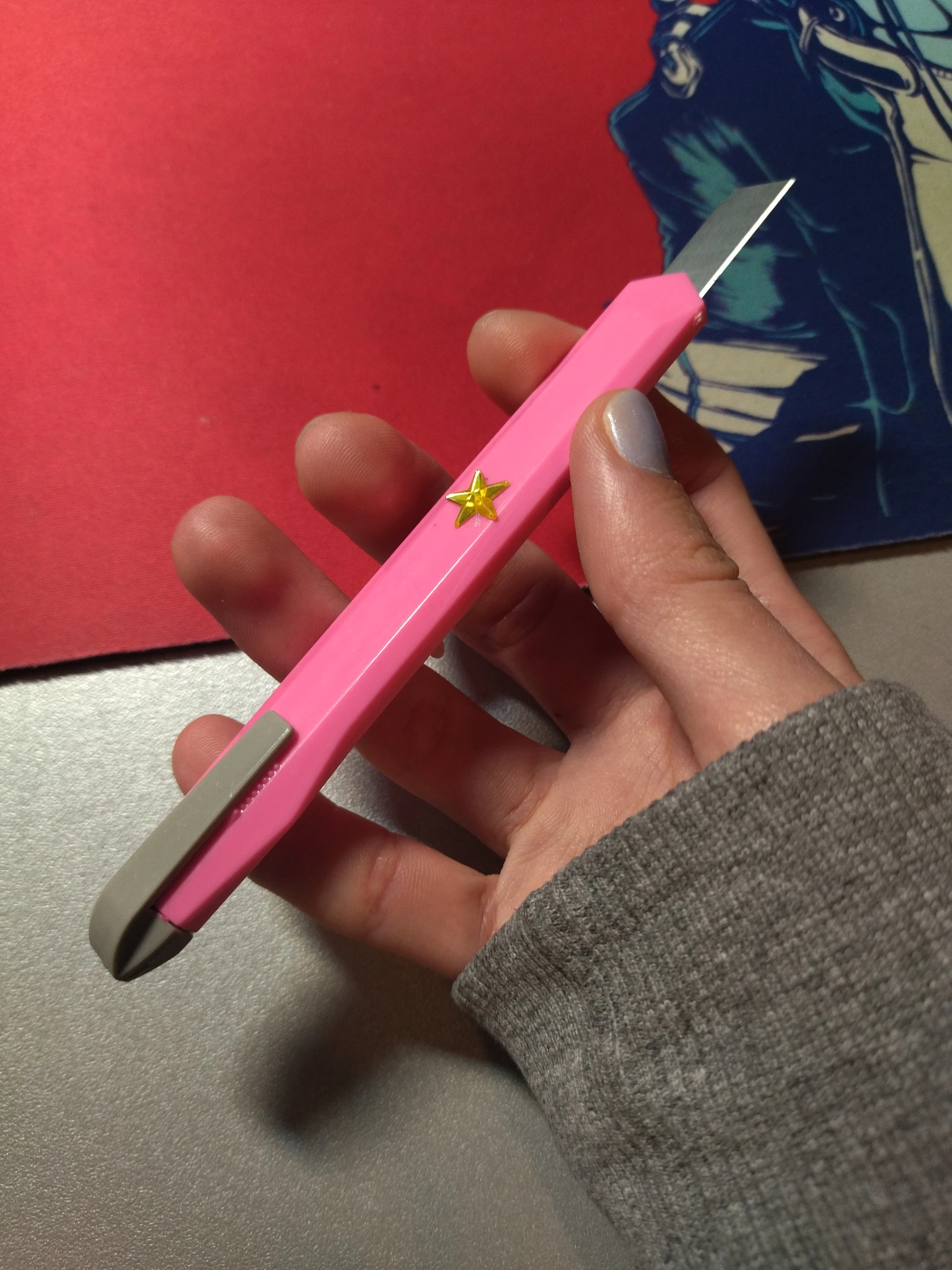 Foto del taglierino rosa temuto in mano, focus sul retro un po' lateralmente