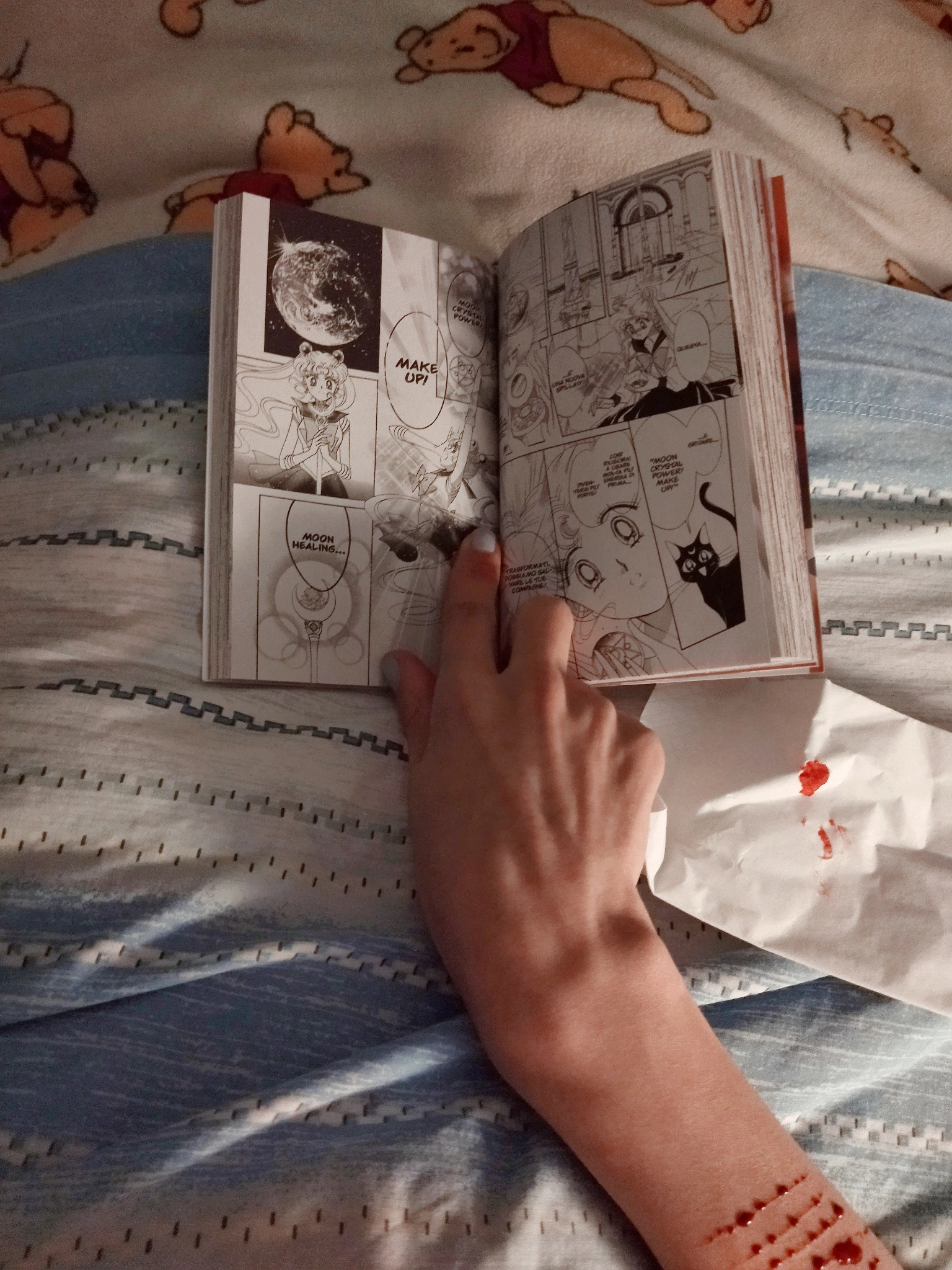 Foto dal mio punto di vista a letto, ho il manga che sto leggendo tenuto aperto con una mano e sul mio avambraccio si intravede qualcosa che non si può dire