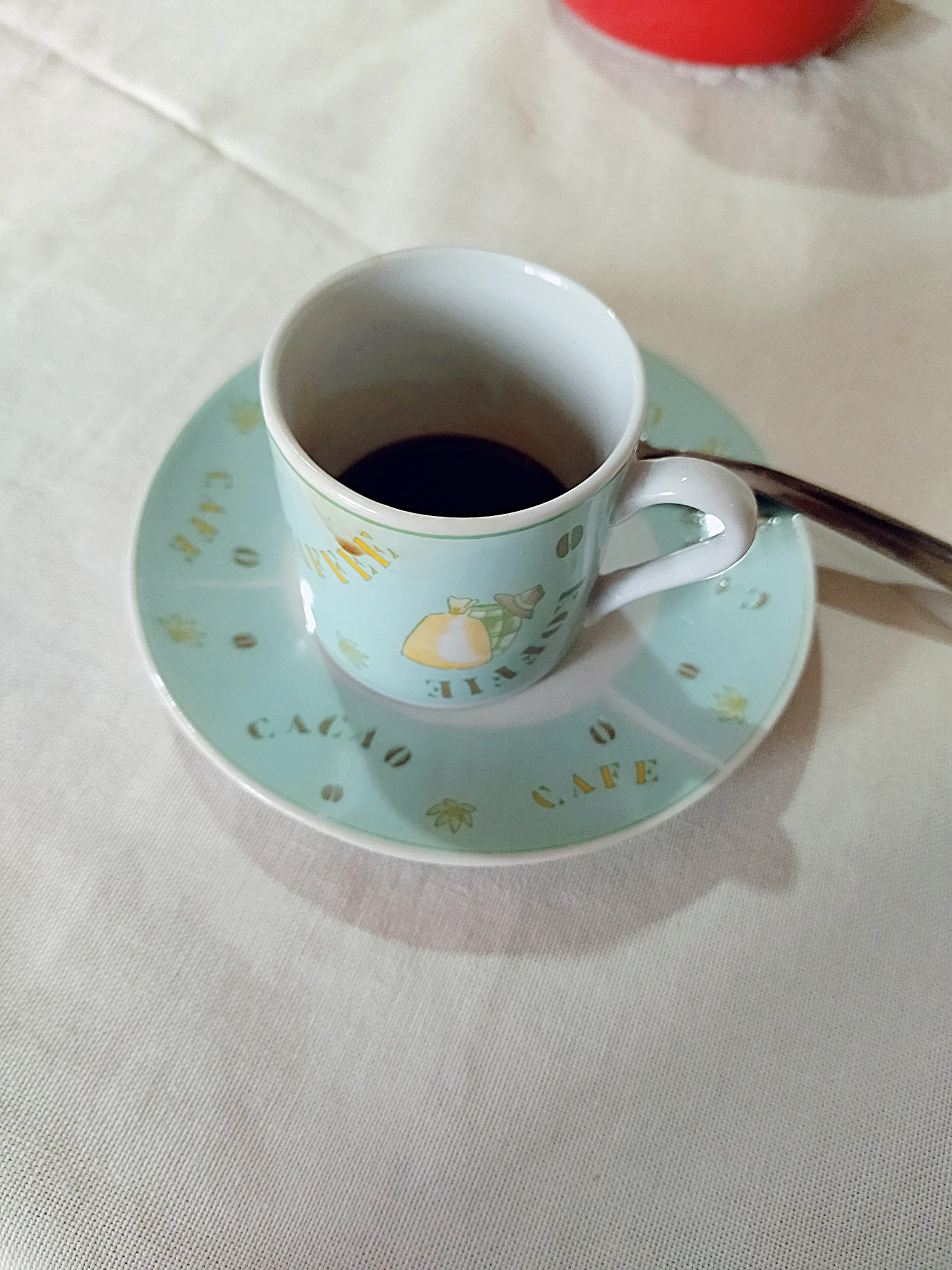 Foto della tazzina di caffè mezza consumata sul tavolo; leggero filtro di B612, colore tendente sull'acquamarina