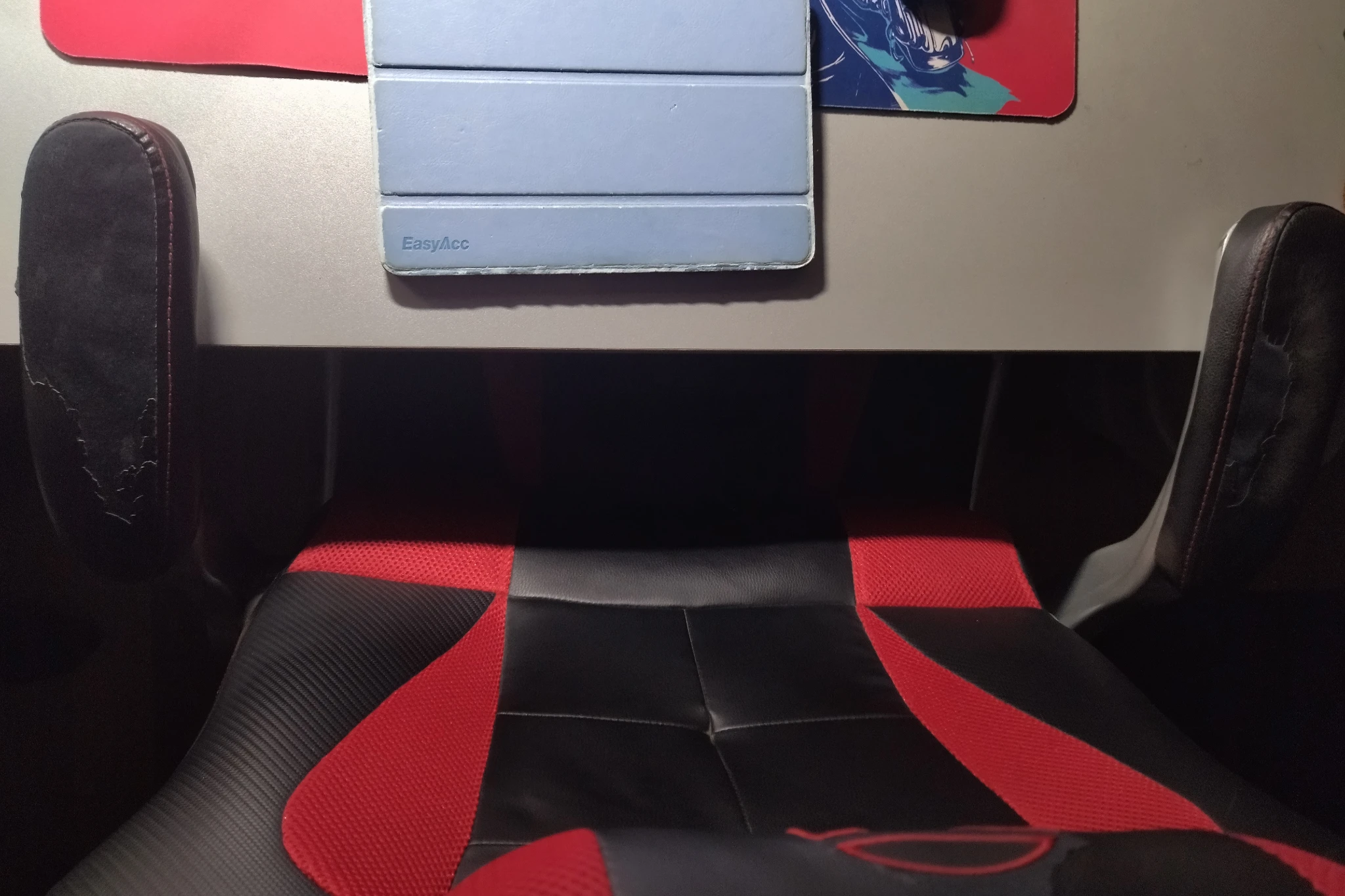 Foto della sedia ancora più troppo abbassata avvicinata alla scrivania dall'alto, si vedono i braccioli un po' incurvati