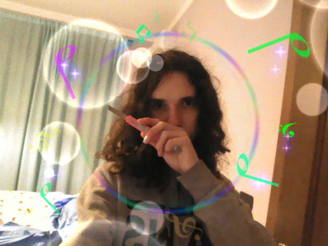 Selfie con modalità Festa del 3DS, meno decorazioni e più luce, con io che ho in mano il taglierino mezzo aperto mentre la mano mi copre giusto la bocca