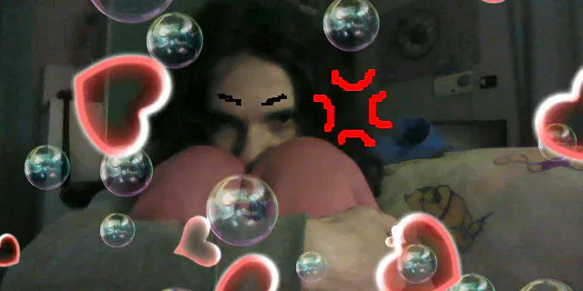 Foto dal 3DS mentre sto sul pavimento, mi tengo la faccia, il braccio e le gambe tutte avvicinate, mentre ho un'espressione realmente vuota e coi disegnini sulla foto resa arrabbiata